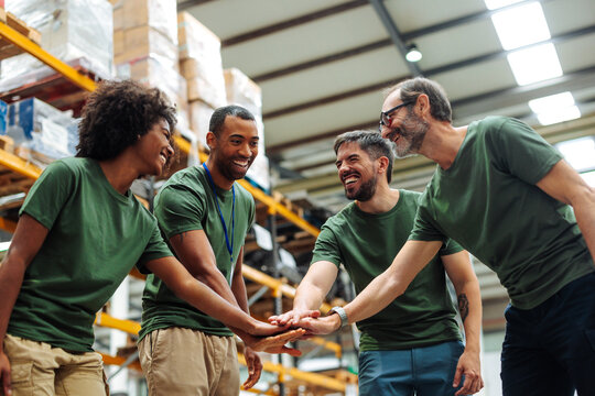 Warehouse workers joining hands for teamwork and success