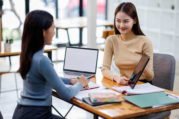 Wall Mural - Two asian female creative agency casual meeting discussion working with laptop, analyze planning and financial statistics and investment market at office.
