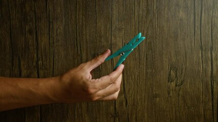 Wall Mural - Man hand holding blue clothespin against a rustic wood background