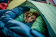© plysuikvv - Woman sleeping peacefully in colorful camping sleeping bag
