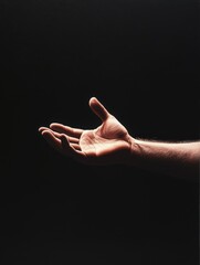 Wall Mural - outstretched hand reaching forward in a dark setting during a moment of connection