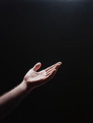 Wall Mural - outstretched hand reaching forward in a dark setting