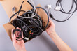 © svittlana - Female hands sorting electronic accessories into a cardboard box, showcasing a circular economy approach to e-waste management.