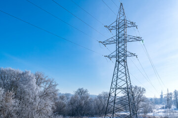 High-voltage wires and poles are covered with frost on a frosty winter day.