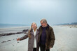 © Marko Geber - Senior couple walking on the beach in winter coats