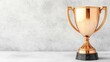 © Tonpoht - Bronze Trophy on Marble: A gleaming bronze trophy stands majestically on a marble surface against a textured gray background.  The image evokes feelings of accomplishment and prestige.