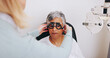 © peopleimages.com - Doctor, optometry and woman with trial lens for eye care, consultation or hands in clinic for health exam. Ophthalmologist, test and senior patient with frame for vision check, wellness or correction