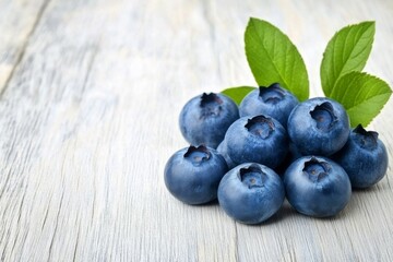 Wall Mural - Fresh blueberries arranged on a wooden surface with leaves in natural light