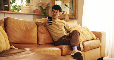 Man, phone and texting on sofa, relax and reading in living room, chat and mobile app in home. Person, smartphone and check notification with contact on lounge couch with social network at apartment