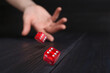 © New Africa - Woman throwing red dice on black wooden table, closeup. Space for text