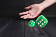 © New Africa - Woman throwing green dice on black wooden table, closeup. Space for text