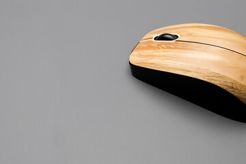 Wooden mouse with black cord. Computer with gray background and a mouse. Wooden mouse with gray wire on a wooden background. A computer mouse with wires on a wooden background lifestyle.