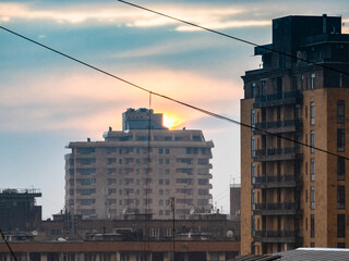 Wall Mural - sunset sun in rainy sky over high-rise buidings