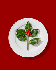 Wall Mural - holly branch with red berries on white plate.