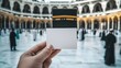 © Nurul - Pilgrim holding blank card with Kaaba and people in the background