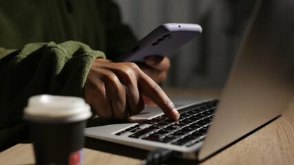 Programmer using laptop and smartphone working at night on cyber security project