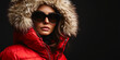 © GS Edwards Studio - A fashionable woman in sunglasses and a red winter coat on a black background, copy space