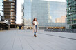 © ADDICTIVE STOCK - Confident woman walking in urban setting holding laptop