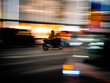 © andrew - Motorcycle with rider in helmet riding through bright Tokyo city lights at night quickly. Speeding or in a rush amongst traffic and urban buildings with vibrant colours and panning motion blur
