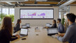 © Aditya - A team collaborates around a large screen displaying dynamic data visualizations. Laptops are used for individual work, fostering a modern and productive workspace.