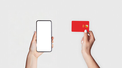Poster - Internet shopping concept. Closeup of girl holdng credit card and mobile phone with blank screen on light background, mockup for design. Panorama