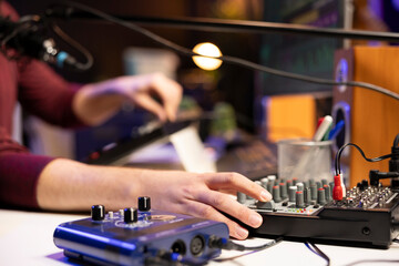 Poster - Sound engineer twisting pre amp knobs to mix and master songs on stereo equipment, working with mixing console and amplifier. Young artist recording soundtracks in his home studio.