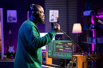 Poster - Young musician songwriter recording an acoustic version of his song, performing live on microphone in home studio. Skilled composer artist producing new tunes with creative lyrics.