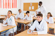 © JackF - Group of young men and women in lab coats lesitening to professor during classes in medical college.