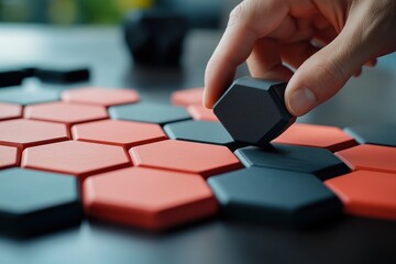 Poster - Hand placing dark hexagon tile onto red and black honeycomb pattern.