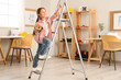 © Pixel-Shot - Cute little architect with measuring tape climbing stepladder at home