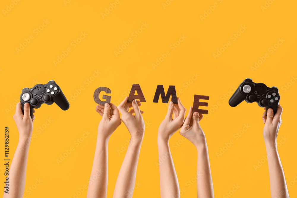 Female hands with word GAME and joysticks on yellow background