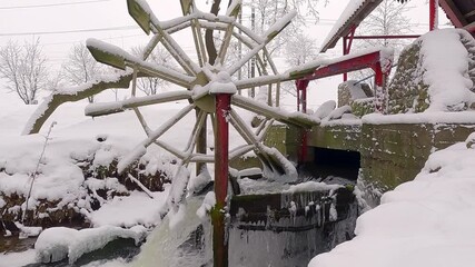 Fototapete - Frozen water mill on Strypa river. Snowy winter scene of botanical garden. Old water mill in Topilche park, Ternopil, Ukraine, Europe. Cold morning view of city park. 4K video (Ultra High Definition).