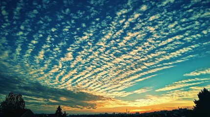 Aufkleber - As the sun begins to set, the sky transforms into a masterpiece of blue and gold, adorned with delicate clouds that ripple like waves. This tranquil moment captures nature’s artistry