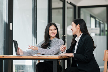 Two women engaged in a business discussion in a modern office, showcasing teamwork and collaboration.