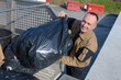 © auremar - happy male worker walking with dustbin on street during day
