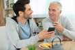 © auremar - happy old father and son having fun using phone together