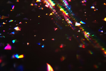 Poster - Colorful light refractions on dark background. Abstract, vibrant, textured light overlay. Multicolored triangles scattered. Cinematic sparkling particles in the air, iridescence festive light effect