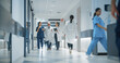© Gorodenkoff - Cheerful Healthcare Team Moving Through a Spacious Hospital Corridor, Preparing for Their Next Shift while Having a Casual Conversation. Female Doctor, Surgeon and Senior Male Working in a Clinic
