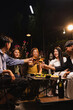 © SOMKID - Group of friends clinking wine glasses in celebration at night, Festival celebration, Happy Asian group friends and dinner party in the night, Friendship and celebration new year concept.