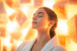 © Anastasia - A tranquil woman relaxes while sitting in a glowing salt room, her eyes closed and face illuminated by the warm light of salt crystals