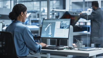 Fototapete - Hispanic Female Automation Engineer Using Desktop Computer to Control Automated Production With Robotic Arms On Modern Electronics Factory, While Indian Assembly Line Worker Using Solder Jet Printer.