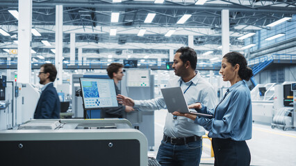Fototapete - Indian Male Chief Engineer And Hispanic Female Supervisor Using Laptop And Talking At Electronics Factory. Man Using Soldering Jet Printer, Explaining Process Behind Production Of Circuit Boards.