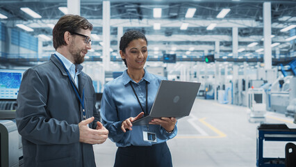 Fototapete - Caucasian Man and Hispanic Female Having a Conversation at an Industrial Facility. Factory Employees Working Together, Using Laptop for Supervising Assembly Process Of New Computer Devices.