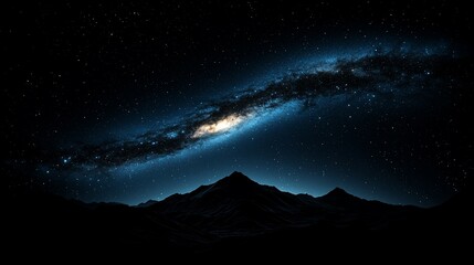 Majestic spiral galaxy over dark mountain range at night.