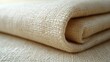 © gentho - A close-up of a rolled piece of beige fabric, showcasing its texture and weave.