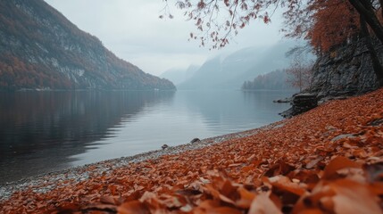 Poster - Autumn leaves by a tranquil lake reflecting mountains and misty skies showcasing serene natural beauty and seasonal change