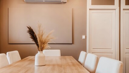 Poster - A serene dining area with a smooth natural wood table surrounded by unadorned white chairs. The walls are painted a soft taupe complemented by a simple vase of dried grasses on the
