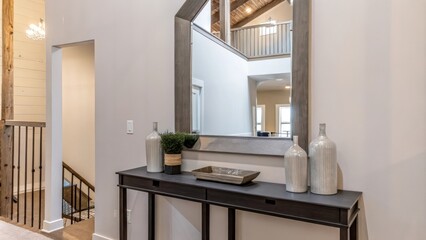 Poster - An entryway featuring a sleek console table made of reclaimed wood styled with a few curated decor items and a mirror that reflects the lofts open layout. The walls are kept