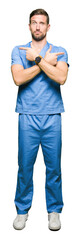 Wall Mural - Handsome doctor man wearing medical uniform over isolated background Pointing to both sides with fingers, different direction disagree