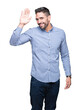 © Krakenimages.com - Young handsome man over isolated background Waiving saying hello happy and smiling, friendly welcome gesture